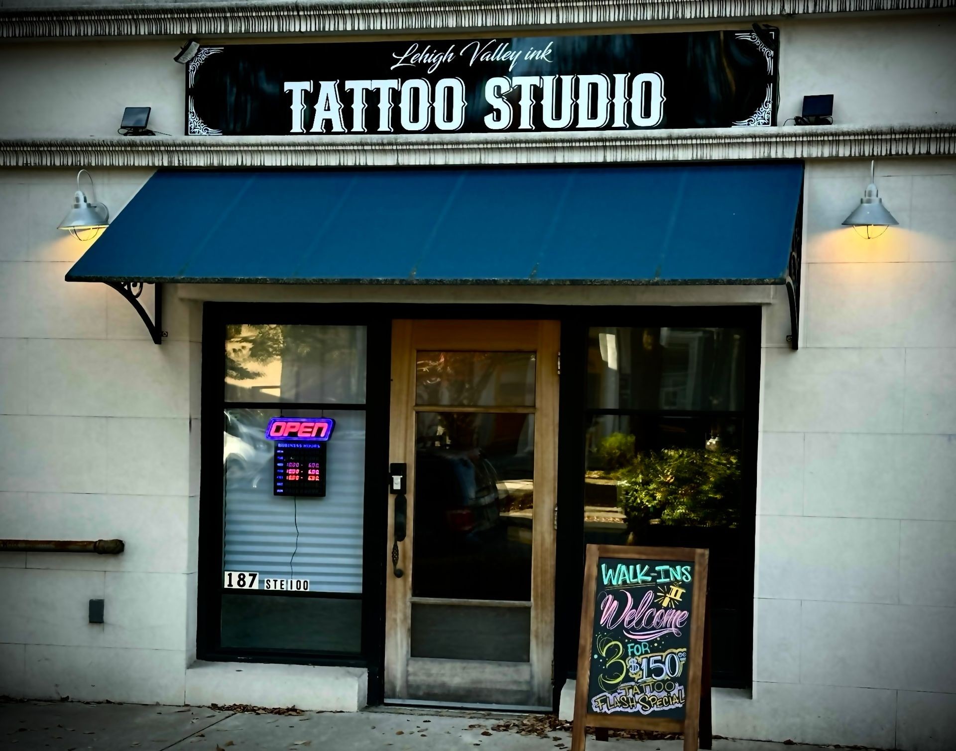 Facade of a tattoo studio with open sign and chalkboard displaying walk-in specials.